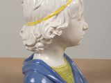 a ceramic bust of a woman with a blue dress and a yellow headband