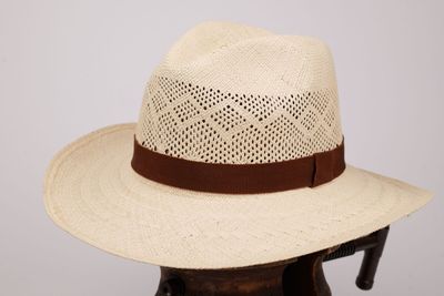 Le chapeau est en paille et est orné d'un ruban marron autour du bord