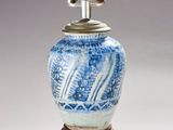 un vase bleu et blanc sur lequel est posée une lampe