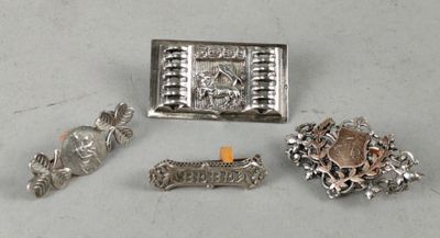 three silver brooches and a silver broochle on a table