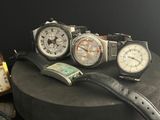 three watches are sitting on top of a round black table