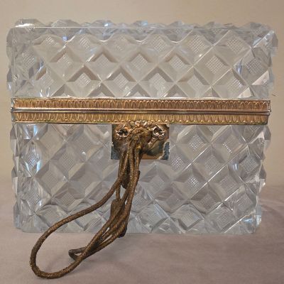 un sac à main en verre transparent muni d'une poignée dorée, posé sur une table