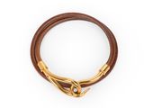 un gros plan sur un bracelet en cuir marron muni d'un fermoir doré