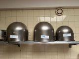 three silver helmets sitting on a shelf in a kitchen