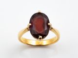 une pierre de grenat de forme ovale sertie dans une bague en or jaune