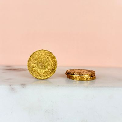 two gold coins sitting on top of a marble counter top