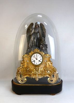 a clock under a glass dome with an angel on it