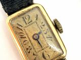 a gold watch with a black band on a white surface