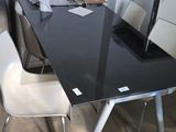 a black table with white chairs and a laptop on it