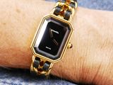 a woman wearing a gold and black watch on her wrist