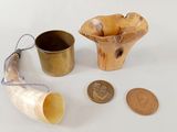 a small horn, a cup, and a coin on a table