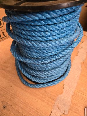 une corde bleue torsadée posée sur une table en bois, avec une boîte en arrière-plan