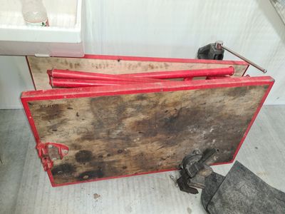 une boîte en bois munie d'une poignée rouge, posée par terre