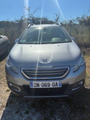 La voiture est garée au bord de la route, au soleil.