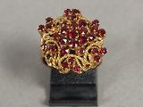 bague plaquée or ornée de pierres rouges, montée sur un support noir