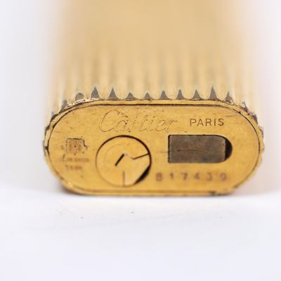a close up of a gold lighter on a white surface