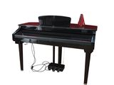 un piano noir posé sur une table, avec un chapeau dessus