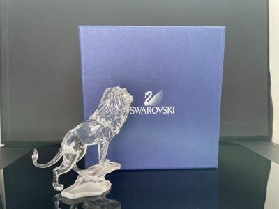figurine en cristal représentant un lion posé sur une table, avec une boîte en arrière-plan
