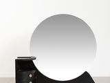 a round mirror sitting on top of a wooden stand