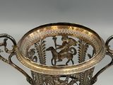 a silver vase that has a horse and horse design on it