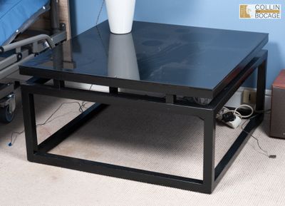 une table basse noire sur laquelle est posé un vase blanc