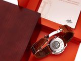 an orange box with a watch inside of it on a white surface