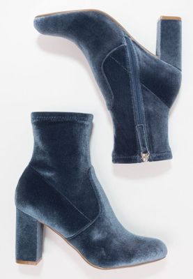 a pair of blue velvet ankle boots on a white background