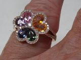 la main d'une femme tenant une bague ornée de pierres multicolores