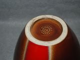 a brown and red vase sitting on a gray surface