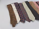 many different ties laid out on a white surface