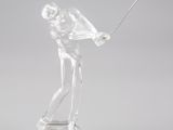 figurine en cristal représentant un homme brandissant un club de golf, posée sur un socle transparent