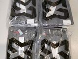 four black and white shirts wrapped in plastic bags on a table