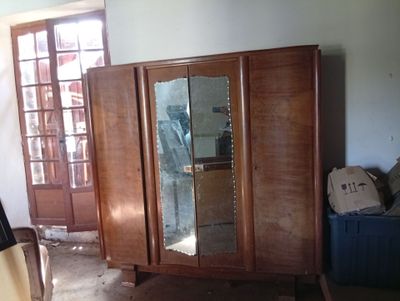 une armoire en bois surmontée d'un miroir, placée dans un coin de la pièce