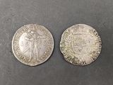 two silver coins, one of which has a man holding a sword and the other of which is holding a