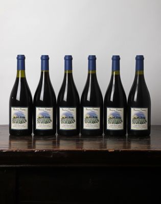 six bouteilles de vin sont posées sur une table devant un mur