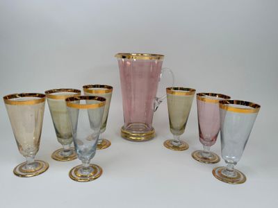 six glasses and a pitcher sitting on a table