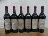 six bouteilles de vin sont alignées sur une table en bois