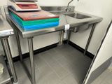 a kitchen with a sink and a counter with a cutting board on it