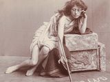 une photo d'époque montrant une femme assise sur une valise