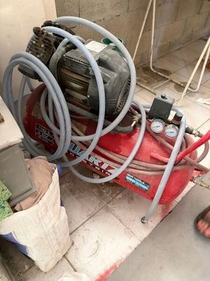 a man that is standing next to a red air compressor