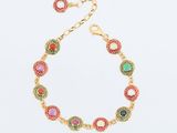 un bracelet en or avec des pierres multicolores sur fond blanc