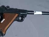 Le pistolet posé sur la table est marron et noir, avec une bande blanche.