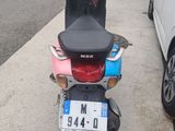 a scooter parked on the side of the road next to a car