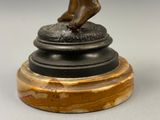 une statue en bronze représentant une personne, posée sur un socle
