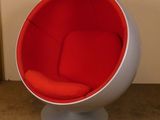 une chaise boule rouge et blanche posée dans une pièce