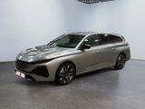 La voiture argentée est garée dans une grande pièce aux murs blancs.