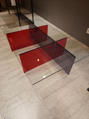 une table en verre avec un plateau en verre rouge posée sur un sol carrelé