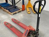 deux palettes et une fourche posées à même le sol dans un entrepôt