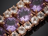 a close up of a bracelet with purple and white stones