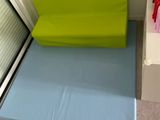 un coussin vert et bleu posé par terre près d'une fenêtre